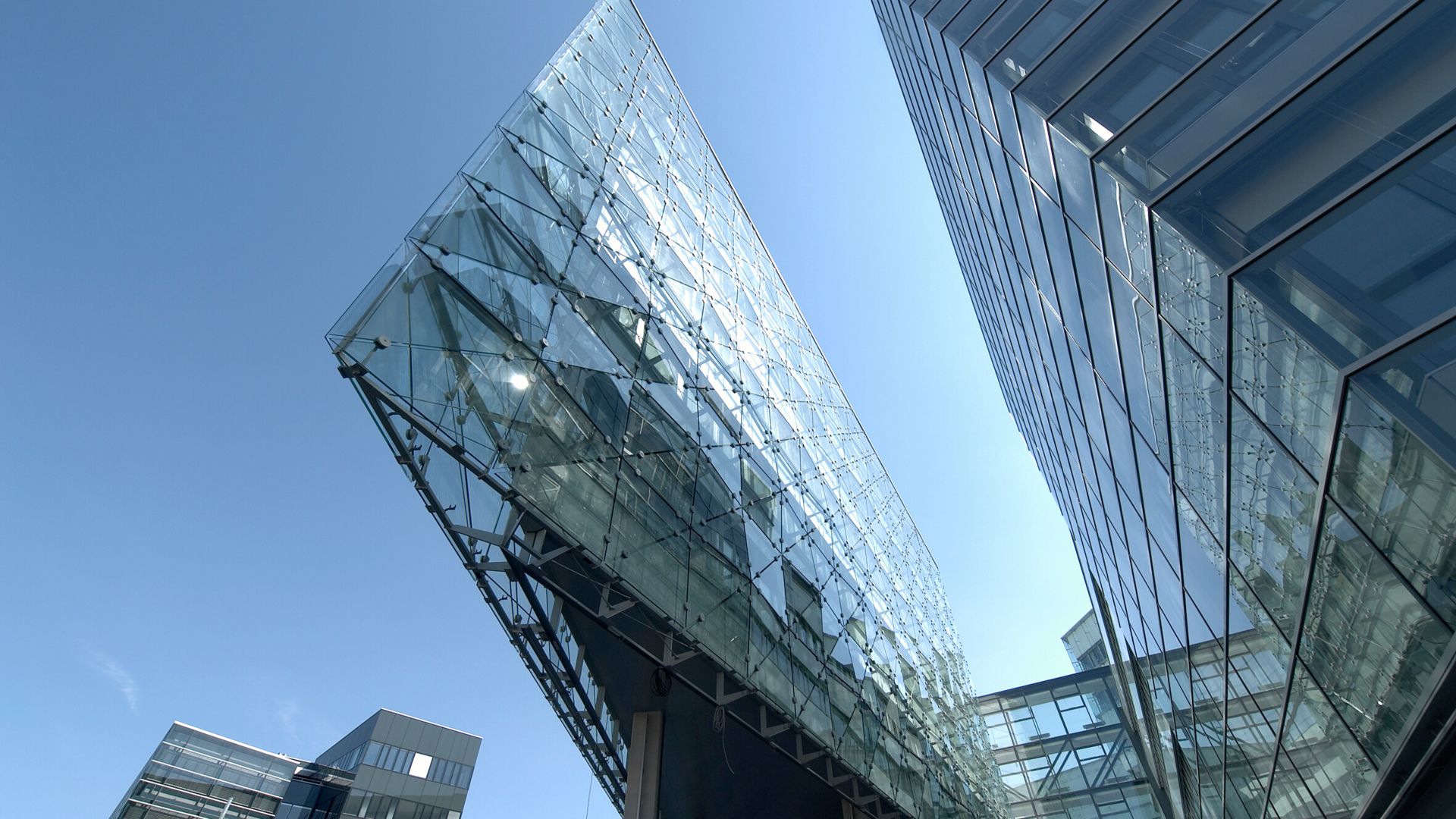 Glass-walled commercial building against a clear sky.