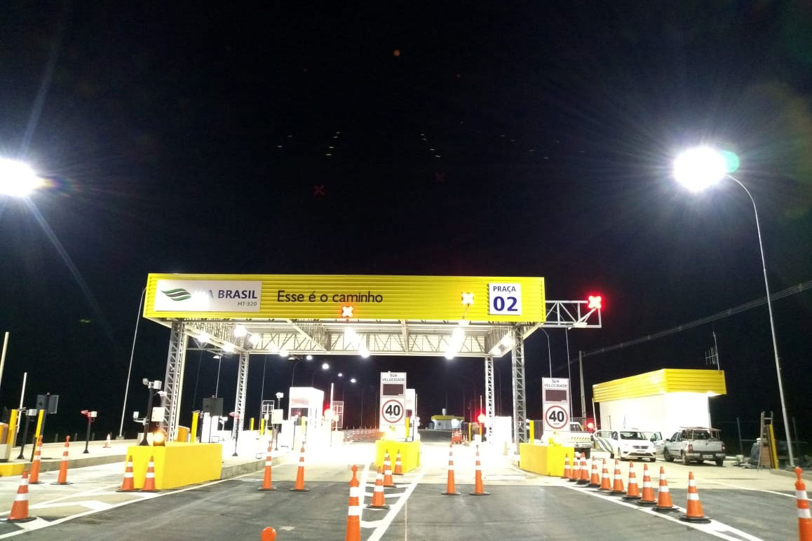 Gelbes und weißes Schild an einer Tankstelle bei Nacht.