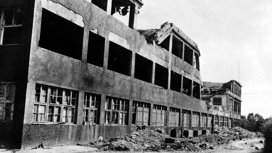 Ein Gebäude mit zerbrochenen Fenstern, das die Zerstörungen der Bombenangriffe auf das Kapsch-Werk im Jahr 1944 zeigt.