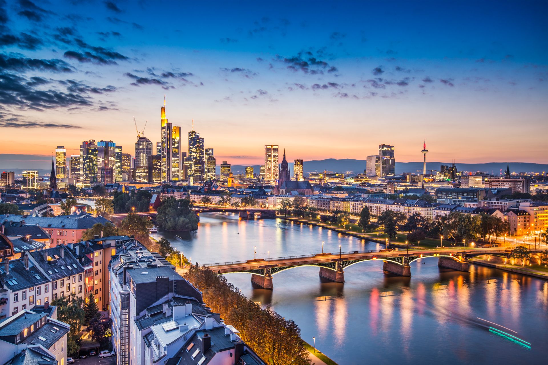 Stadtansicht mit einer Brücke über einen Fluss bei Sonnenuntergang.