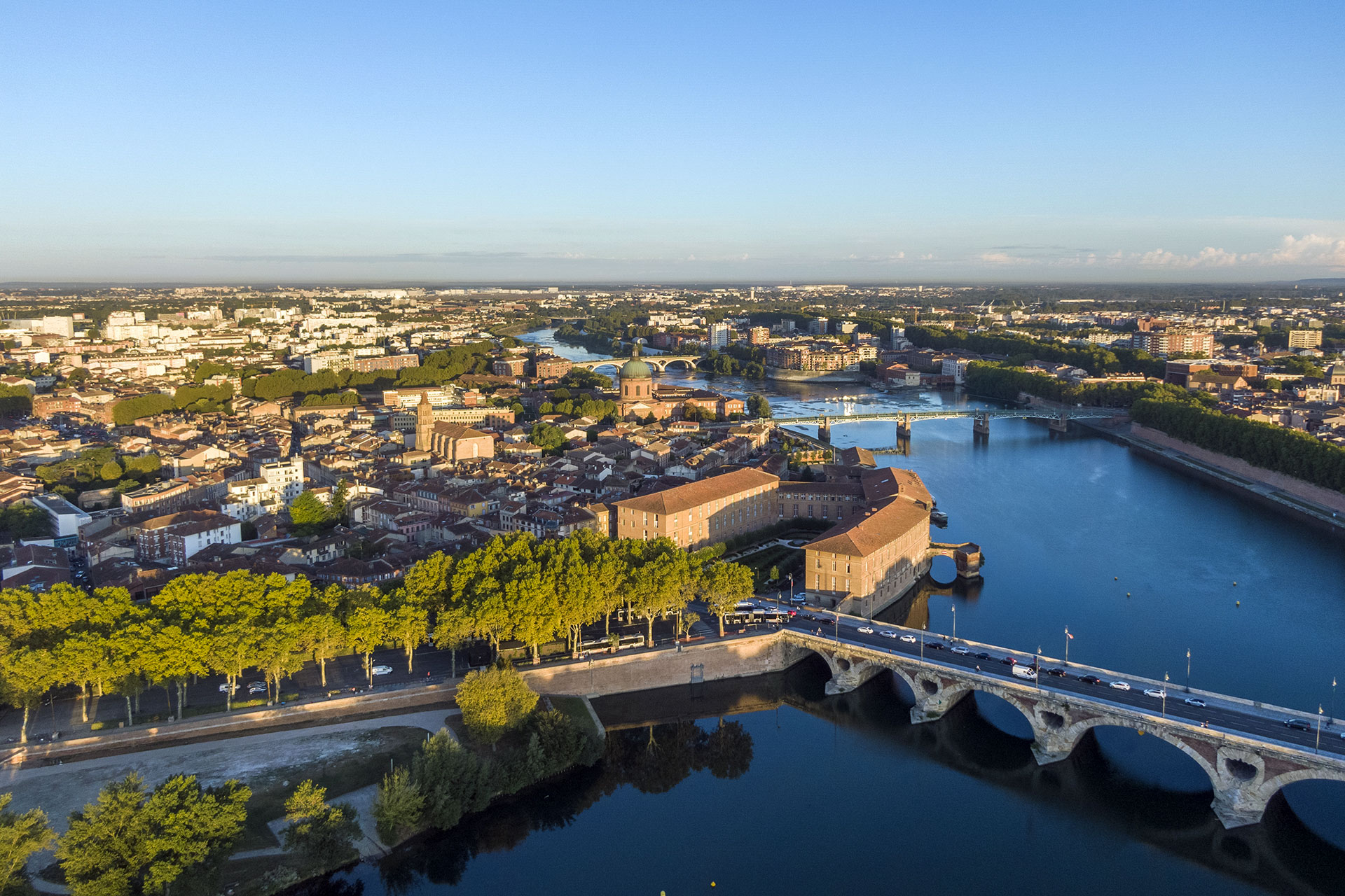 Brücke über einen Fluss mit Bäumen und Gebäuden im Hintergrund