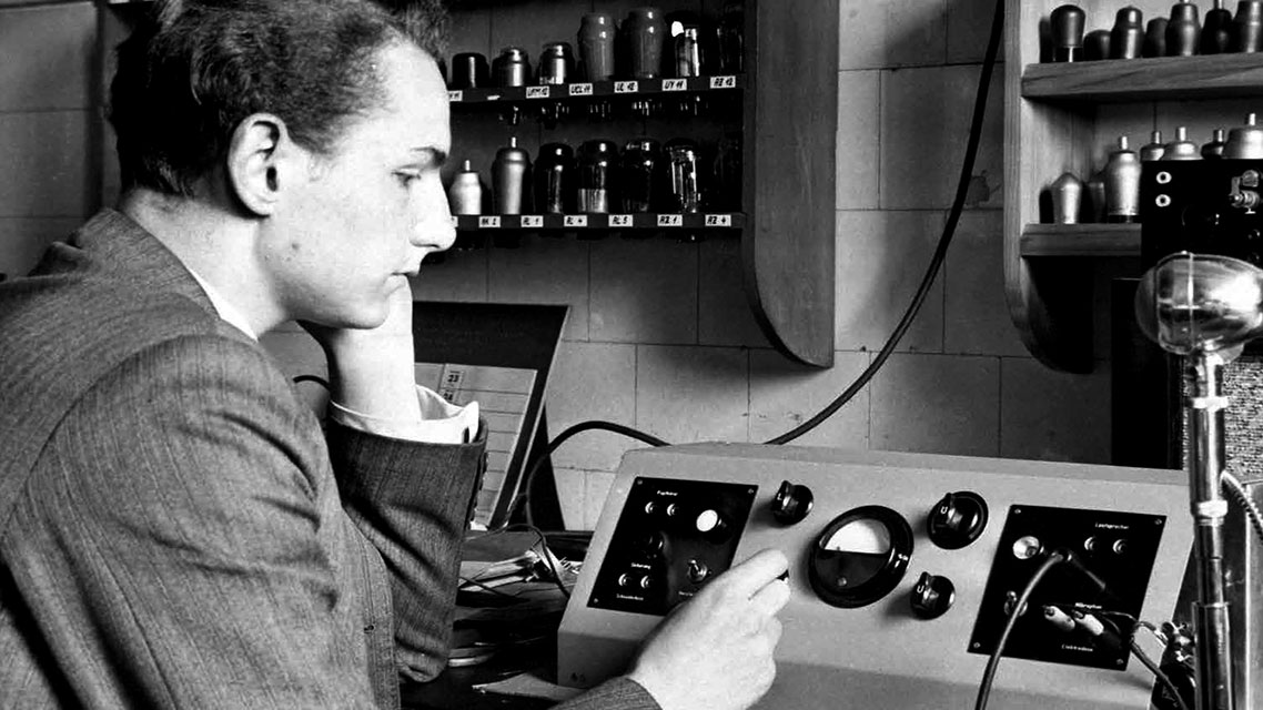 Ein Mann arbeitet an einer Maschine in einem historischen Kontext der Kapsch Unternehmensgeschichte.