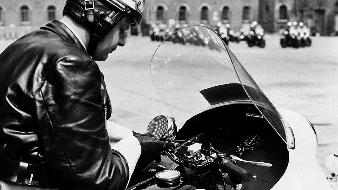 Ein Mann in Lederjacke auf einem Motorrad im Freien.